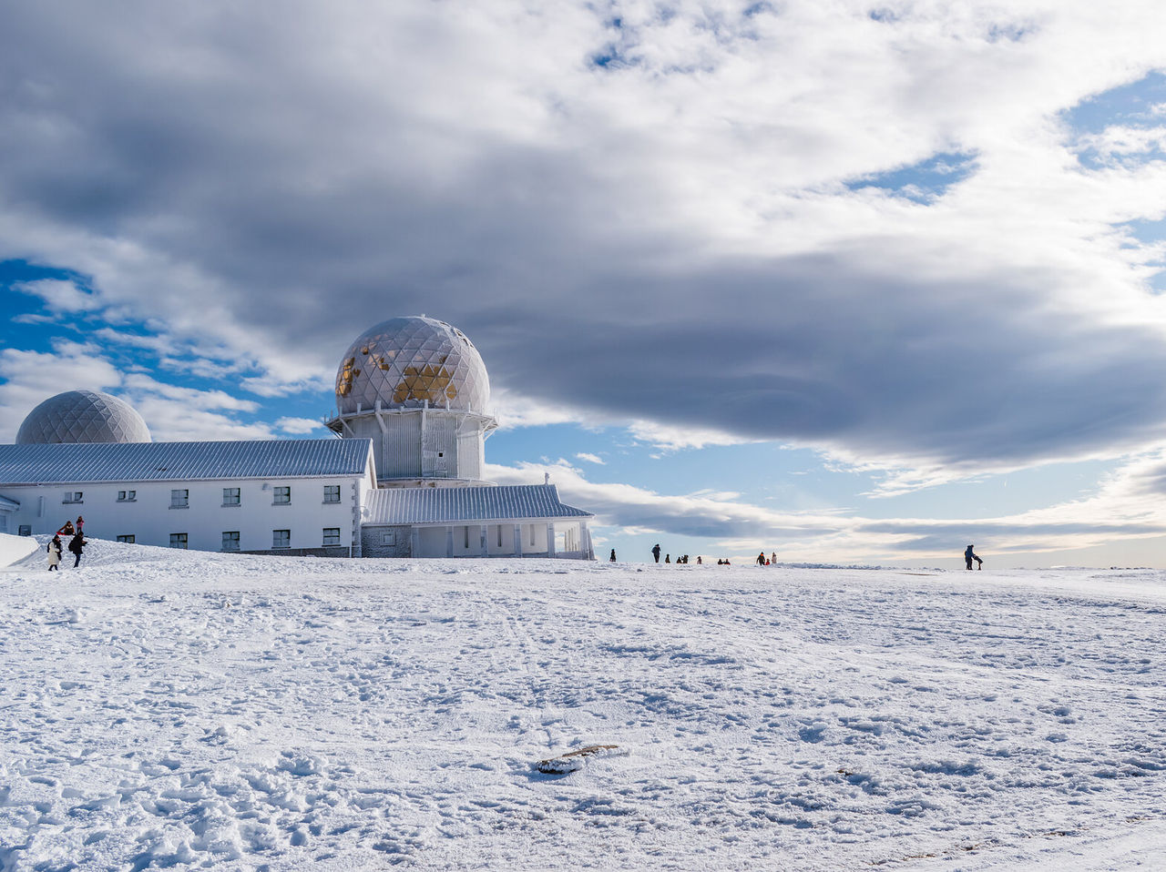 Explore Hotels in Central Portugal featuring a snowy mountain observatory beneath dramatic winter clouds