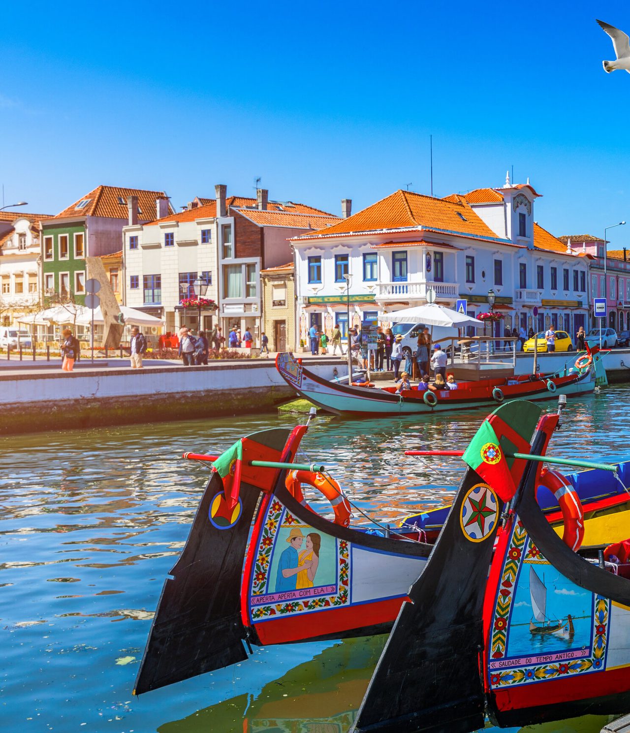 Explore Hotels in Central Portugal featuring colorful canal boats beside waterfront buildings under blue skies