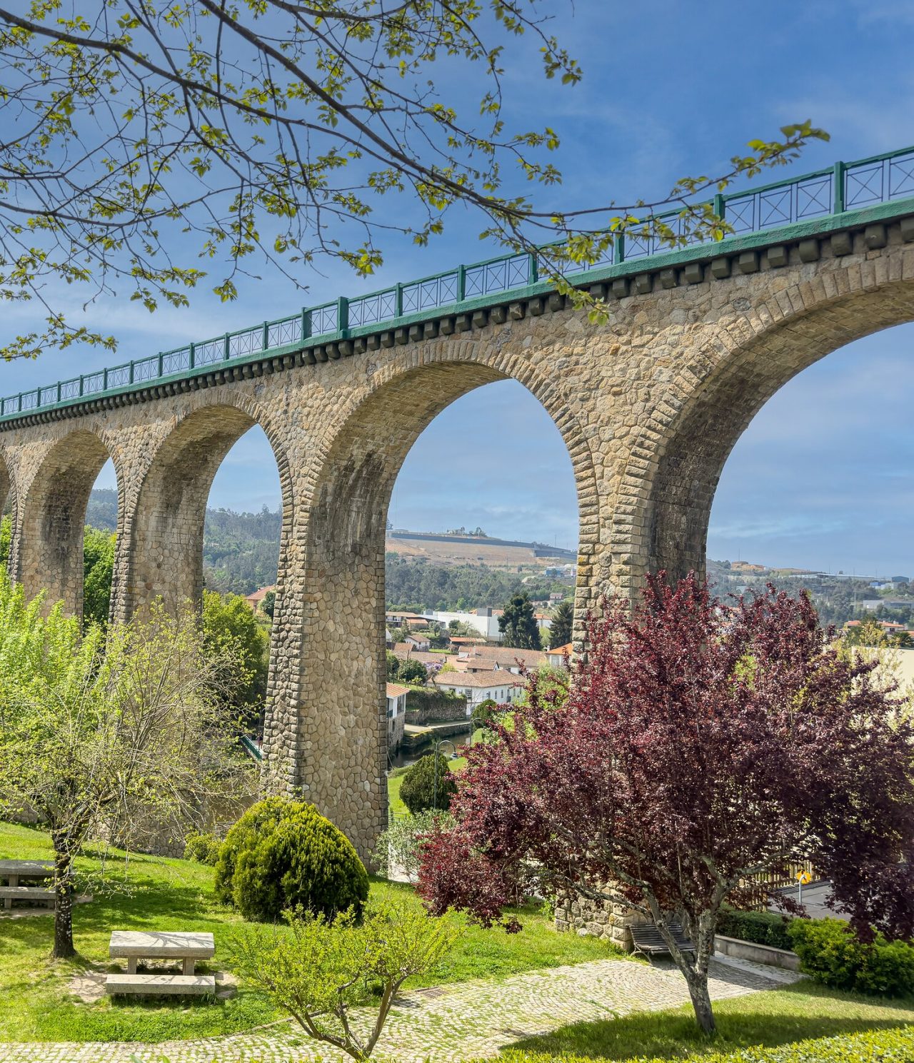 Explore Hotels in Central Portugal featuring a stone railway viaduct rising above trees and hillside homes