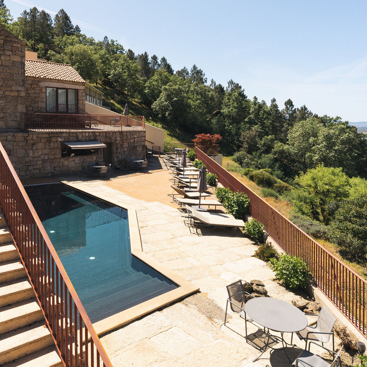 Outdoor pool at Pousada Convento de Belmonte, with a view of nature, several loungers, and tables with chairs