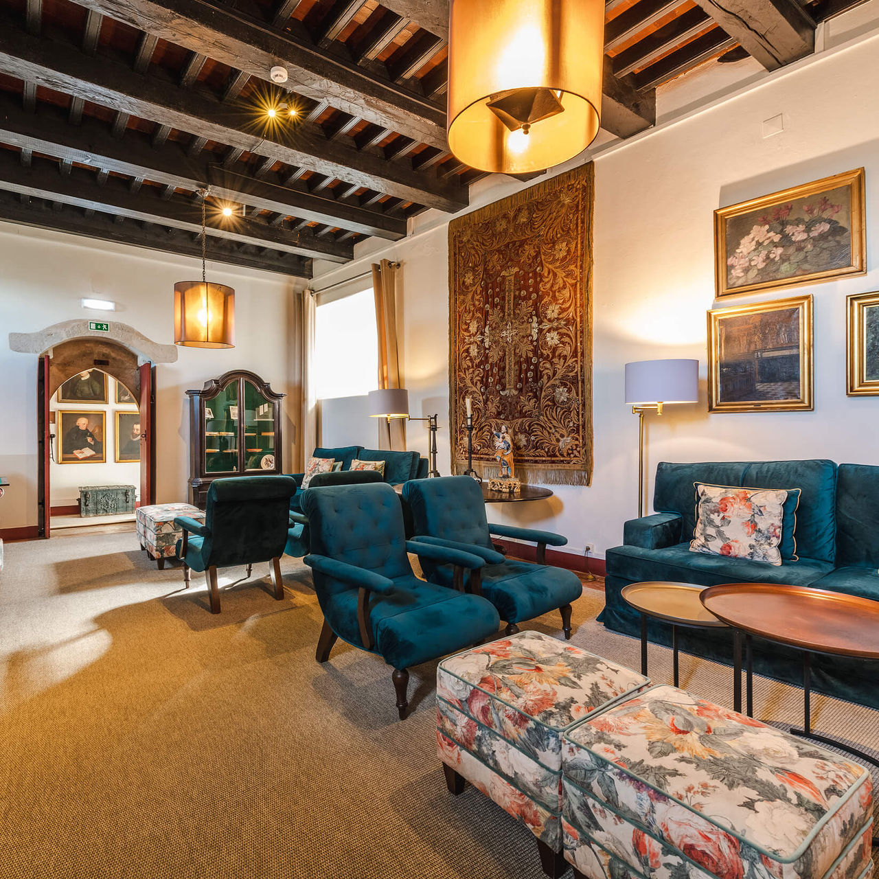 Lobby of Pousada Castelo de Óbidos, historical hotel in Óbidos, with blue sofas and armchairs and floral-patterned puffs