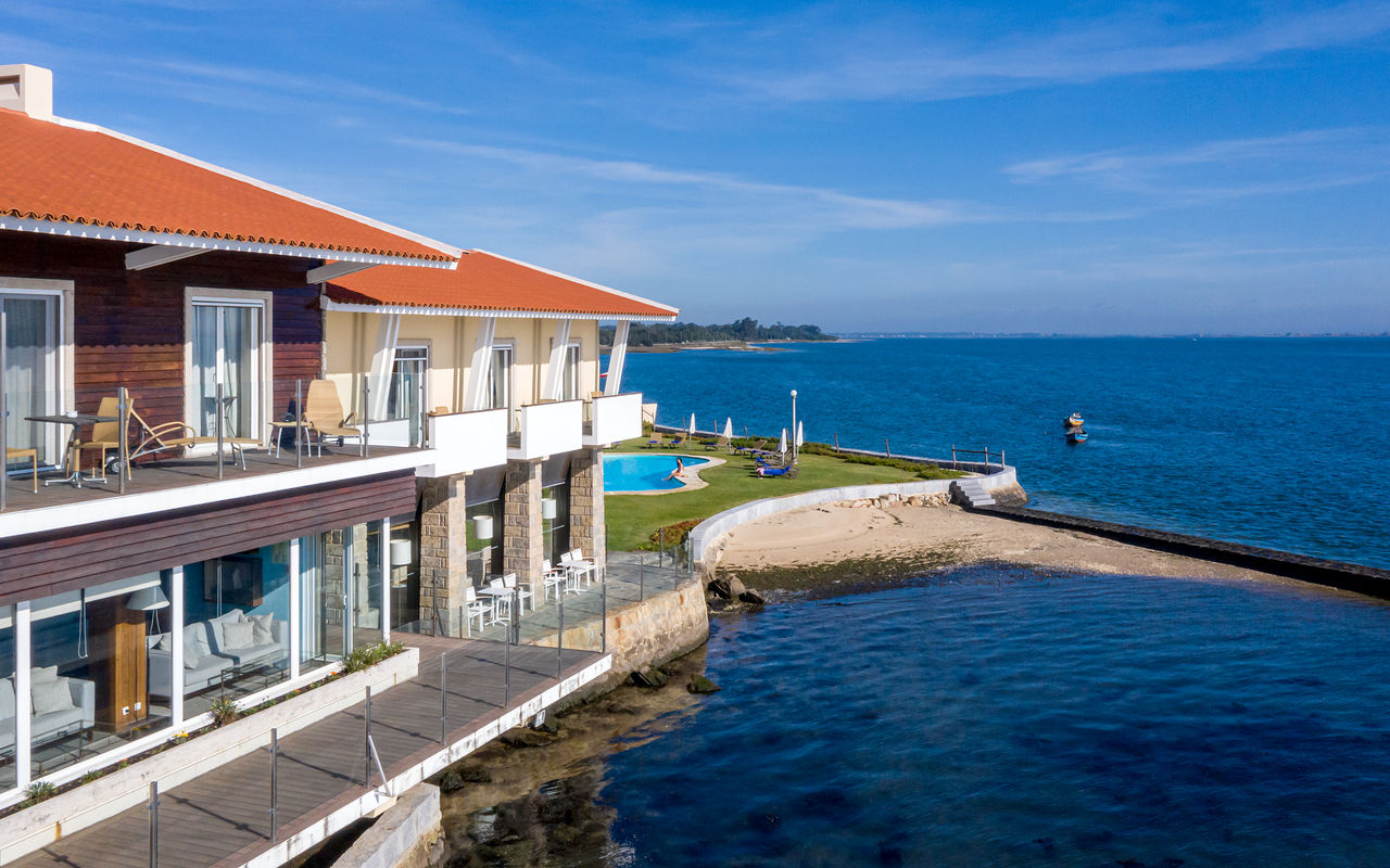 Facade of Pousada Ria in Aveiro, with a pool, leisure area, and direct access to the beach, facing a calm sea