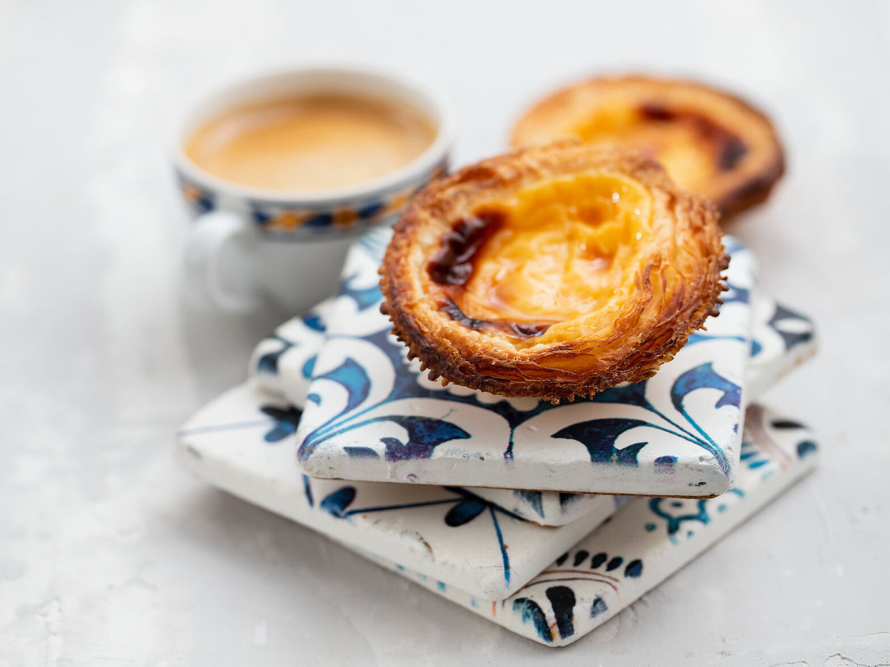 Explore Hotels in Lisbon featuring Portuguese custard tarts beside a coffee cup on patterned ceramic tiles