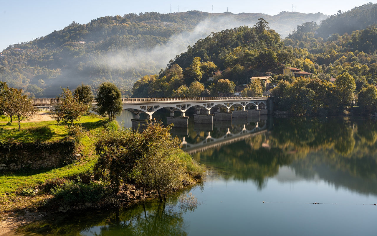 Landscape of northern Portugal with a stone bridge over a river, surrounded by green hills