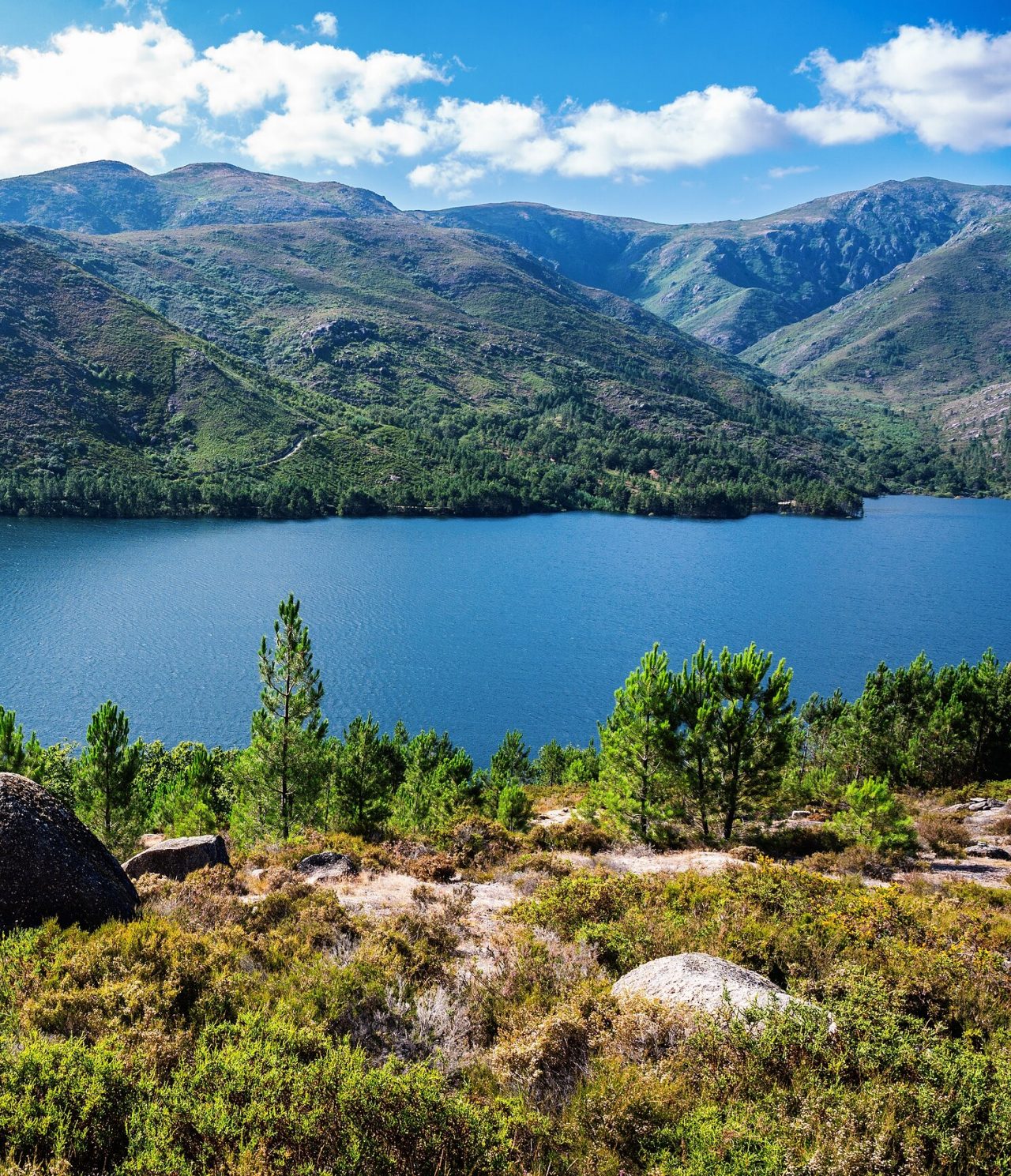 Explore Hotels in Northern Portugal featuring a mountain lake framed by green hills beneath bright clouds