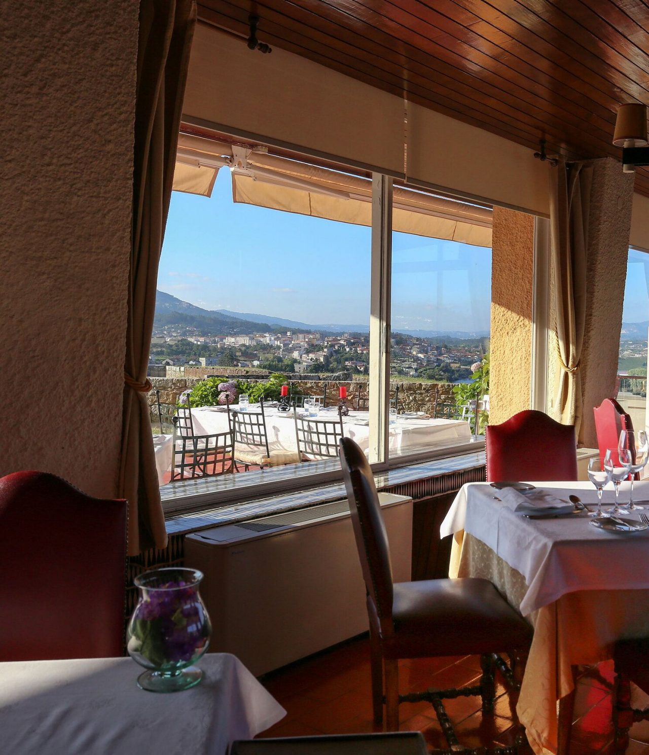 The restaurant of the Charming Hotel in Valença has tables indoors and a patio outside with a view of the river