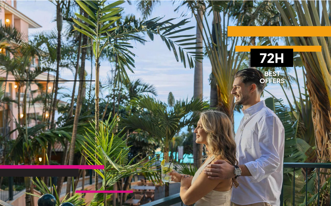 Couple holding drinks beside tropical palm trees and resort balconies during a 72 hour hotel offer