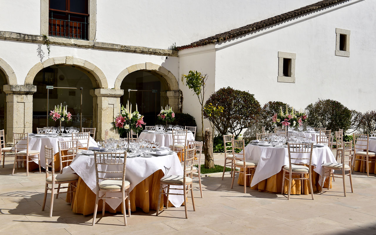 Historic outdoor venue decorated for a wedding, with round tables and magnificent flowers at Pousadas de Portugal