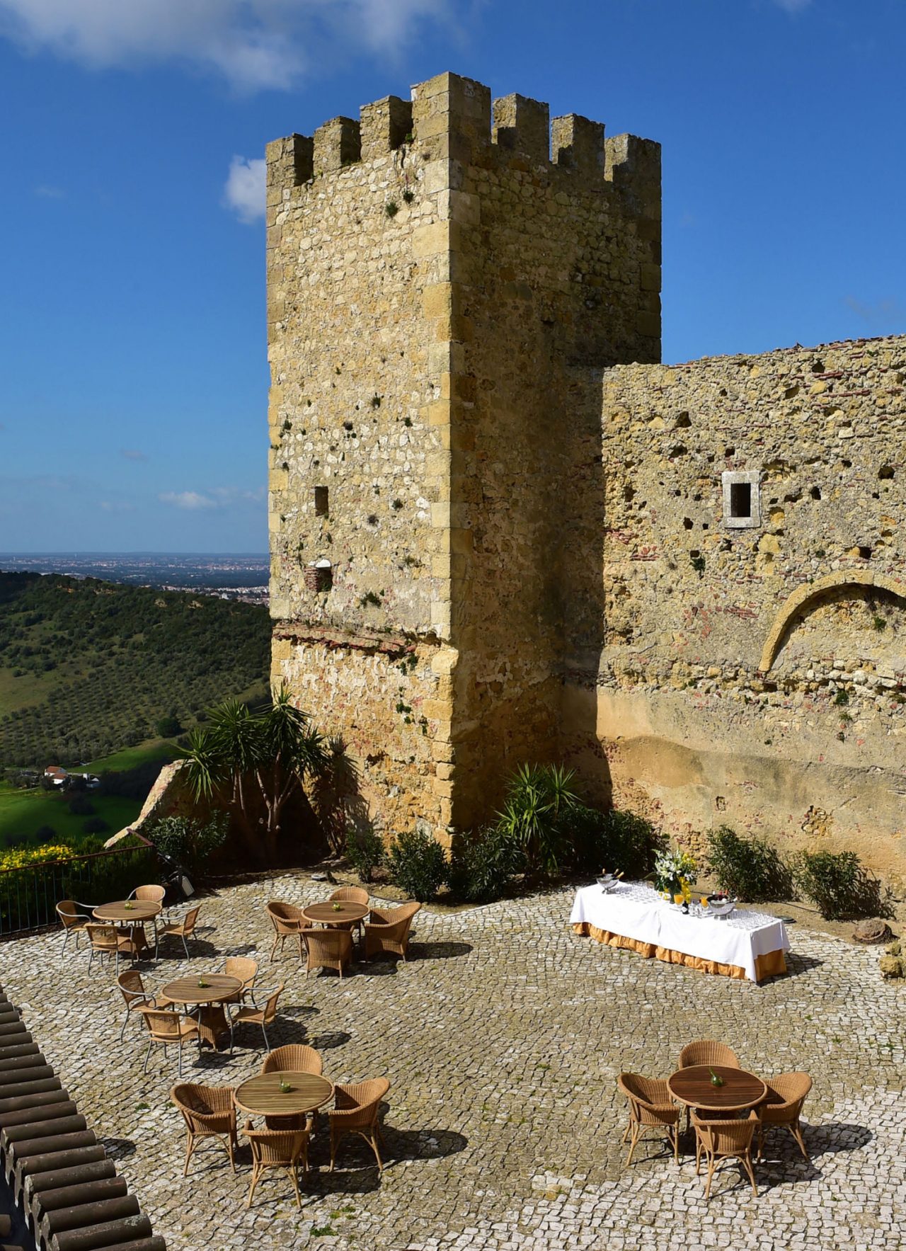 Outdoor space of a castle on a sunny day, set up for meetings and conferences with multiple tables and chairs
