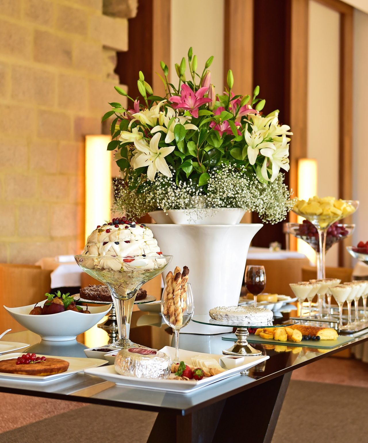 Meeting facilities featuring a buffet table with pastries, desserts and tall floral arrangements indoors
