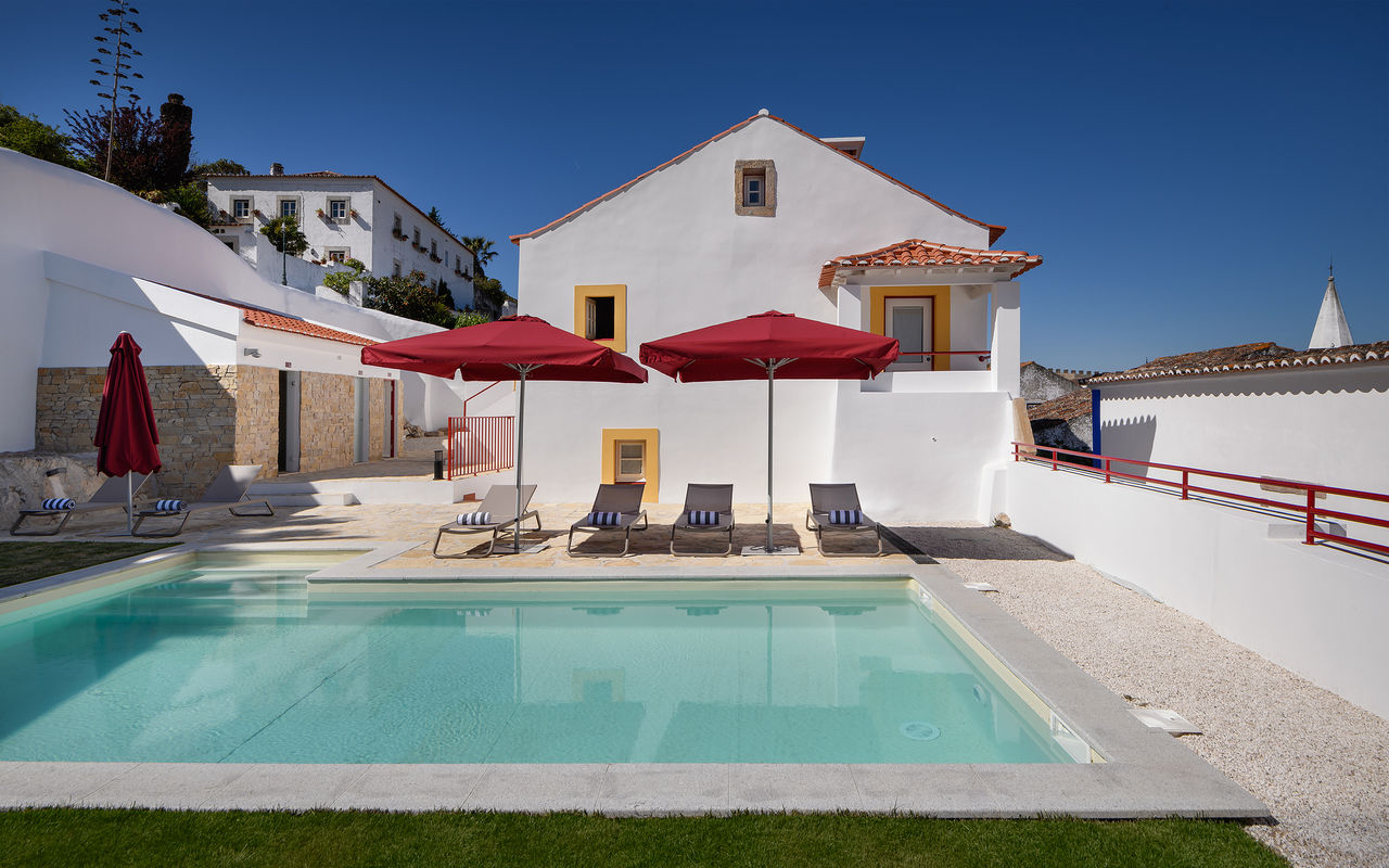 Vista de la piscina exterior de Casa Lidador - Óbidos, hotel de encanto en Óbidos, con tumbonas y sombrillas