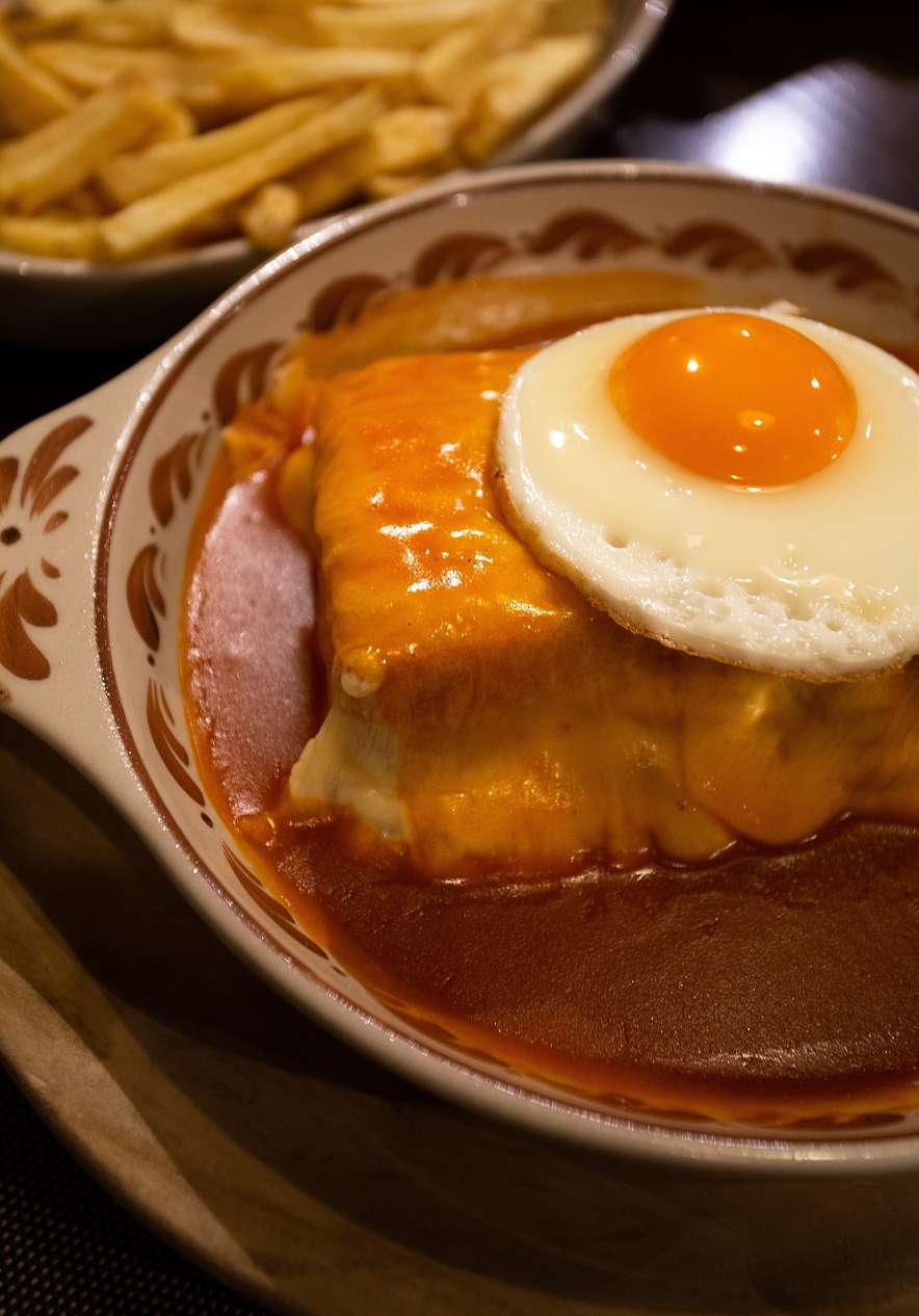 Francesinha tradicional, uno de los platos más famosos de Oporto, con queso, huevo, salsa picante y patatas fritas