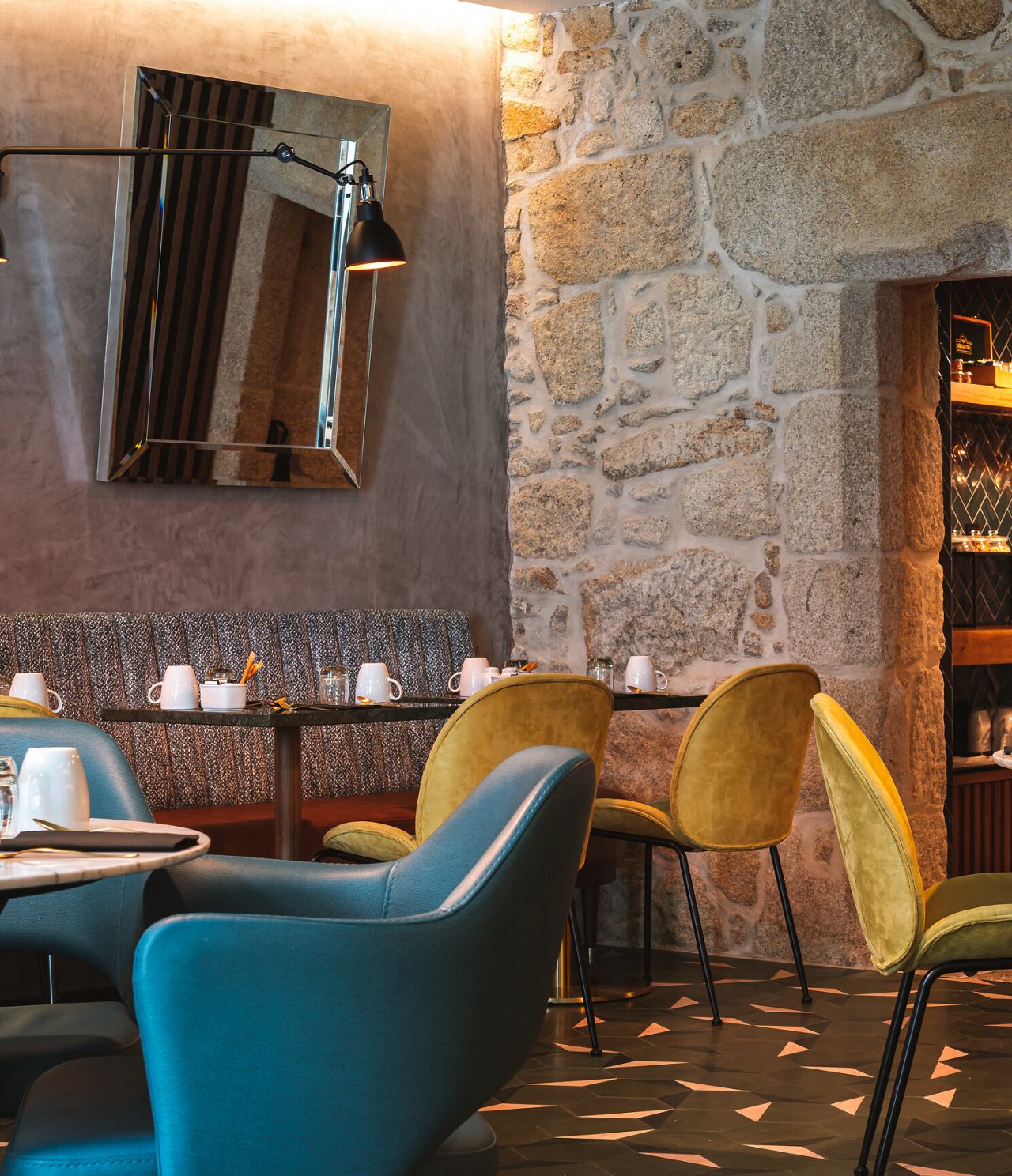 El restaurante P Gastro Bar del hotel en el centro histórico de Oporto, tiene sillas azules y amarillas y paredes de piedra
