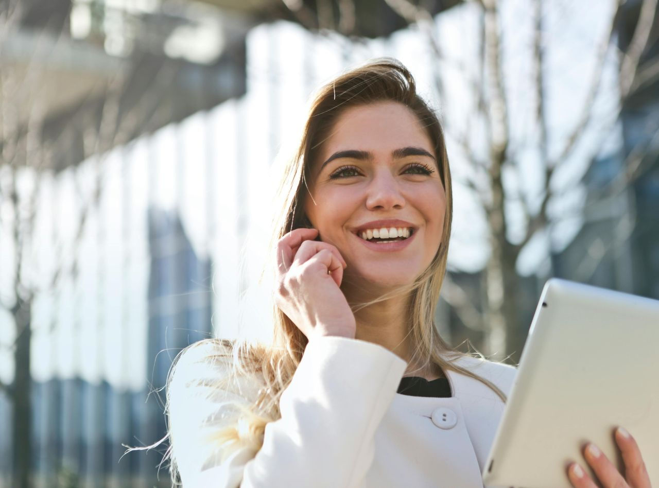 Dame souriante répond à un appel d'un client tout en tenant une tablette à la main