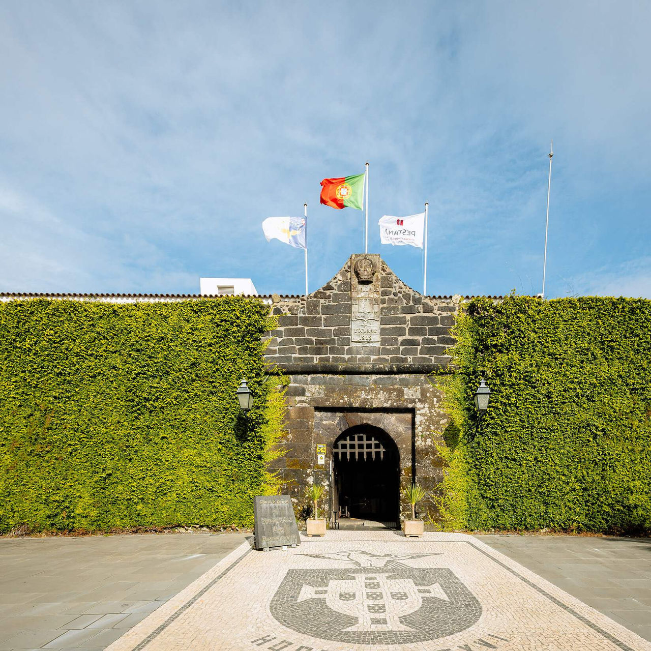 Entrée principale de la Pousada Forte Horta, un hôtel historique à Horta, Faial, avec un mur couvert de plantes