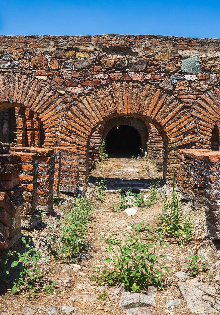 Anciennes ruines romaines de Pisões, avec des briques entassées et divers arcs formant un tunnel