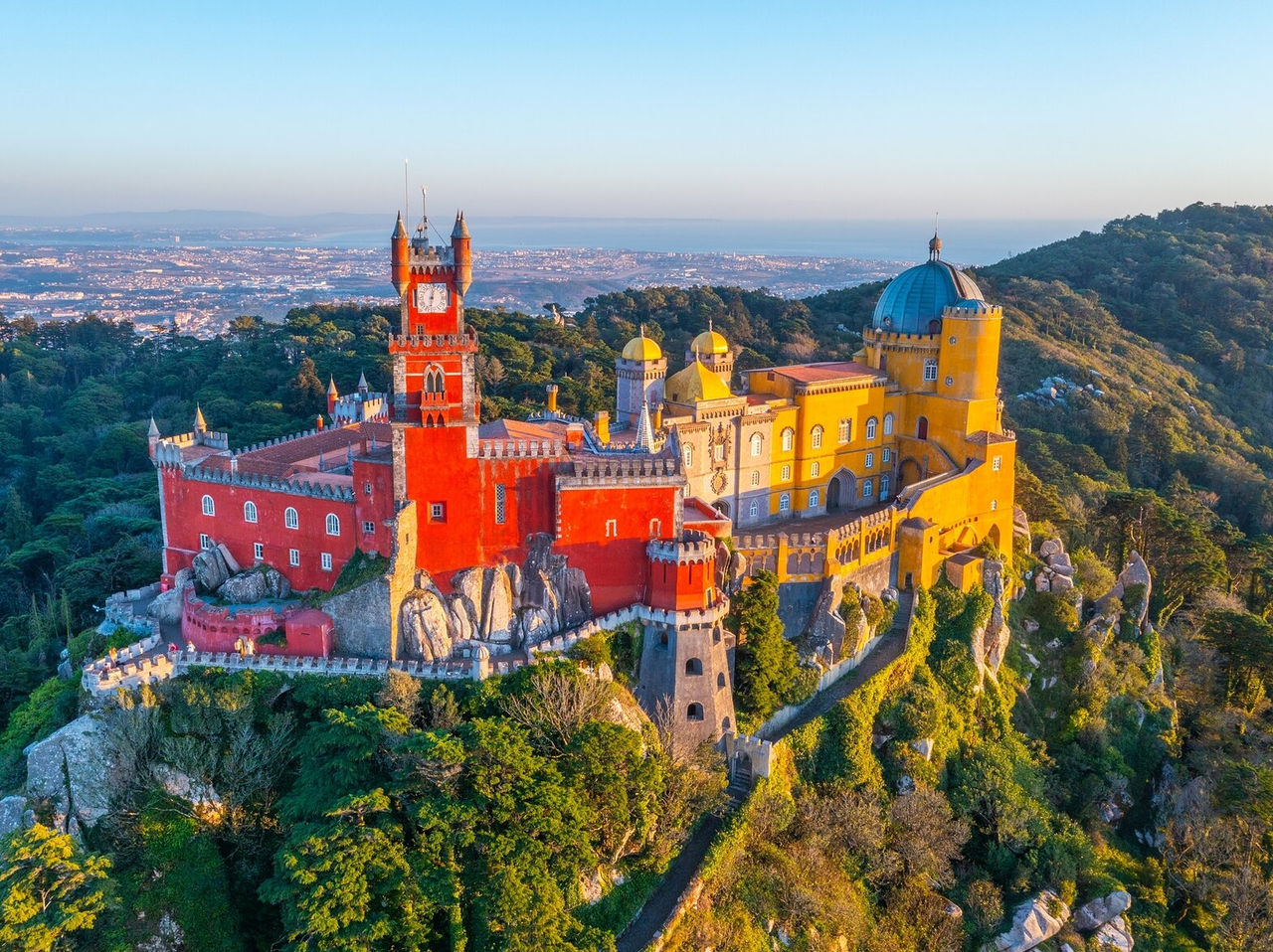 Explorez Hôtels à Lisbonne avec une vue aérienne du palais coloré entouré de collines boisées à Sintra