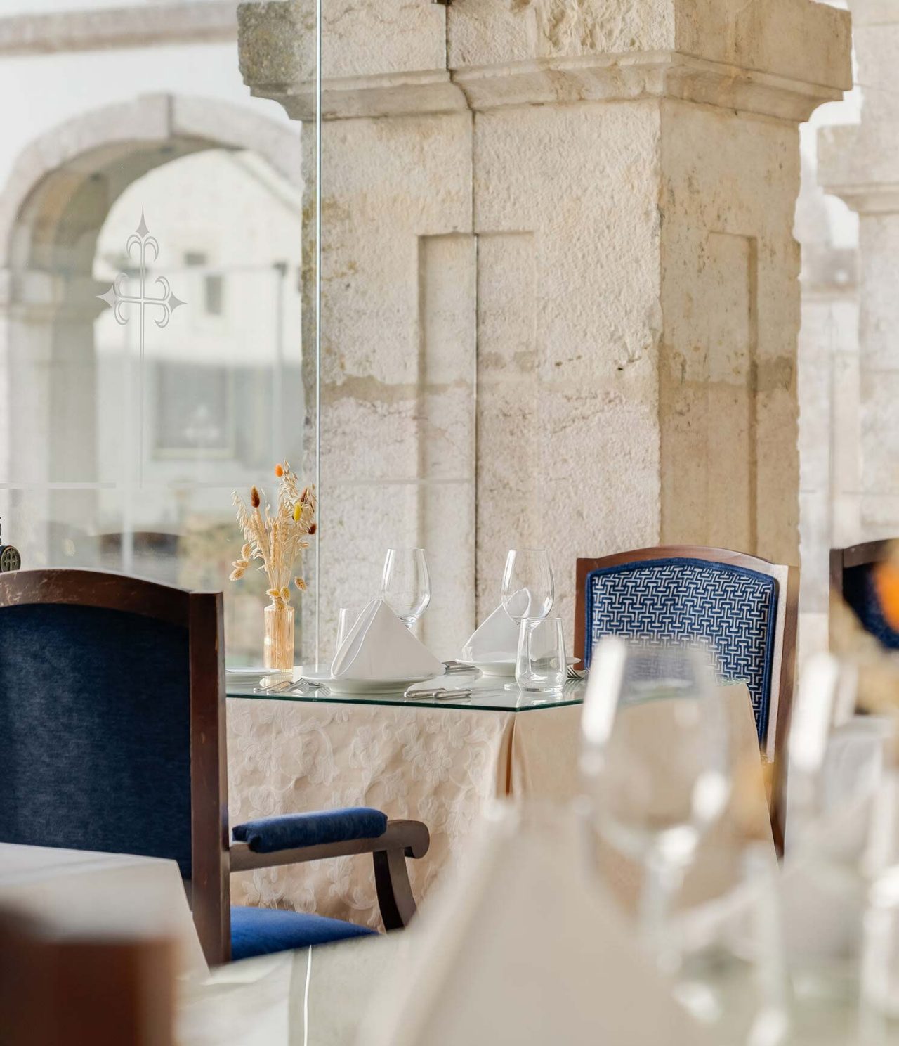 Restaurant du Pousada Castelo Palmela Hôtel à Palmela, tables dressées près des arches en pierre avec verres et serviettes