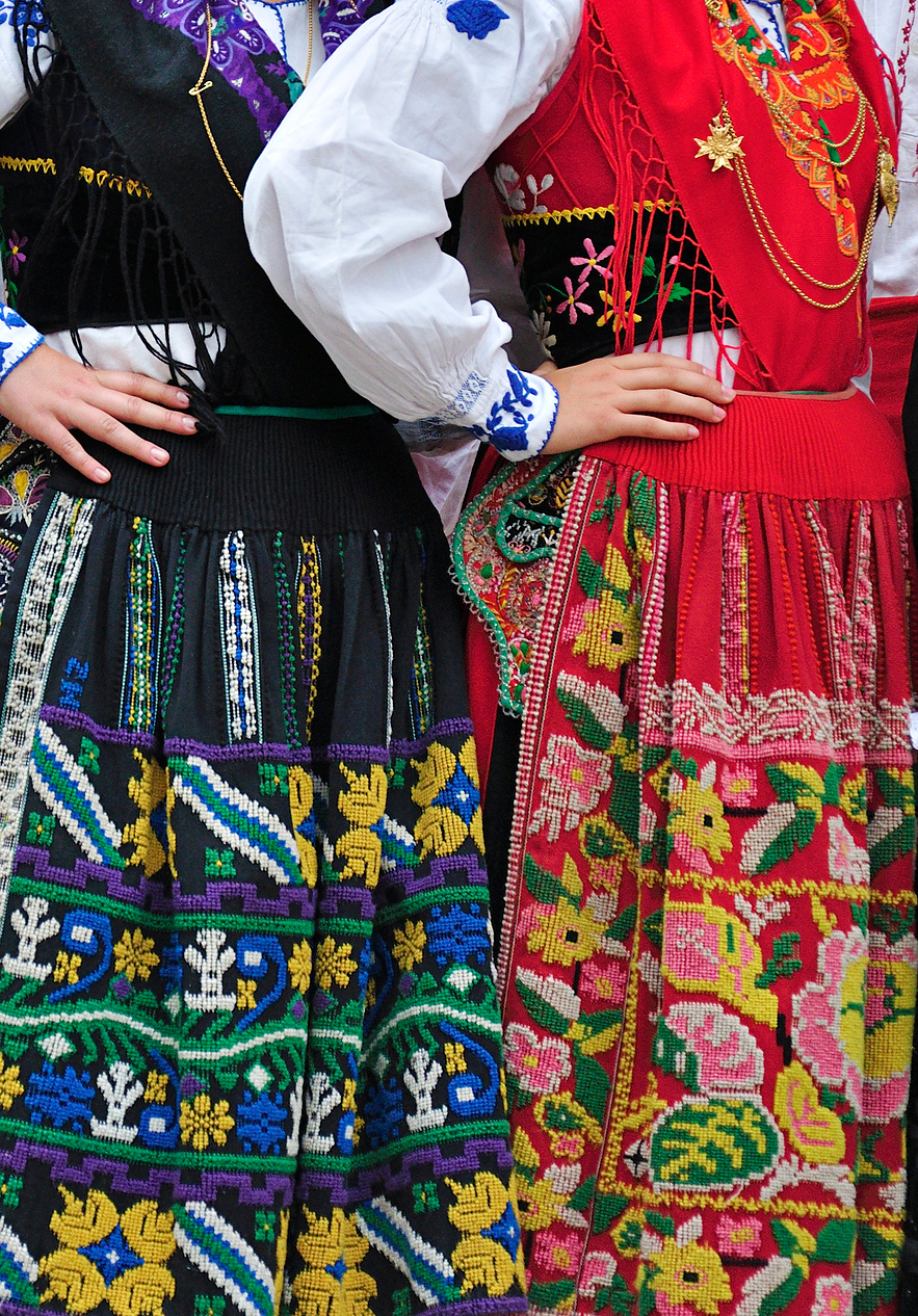 Deux femmes en costume traditionnel minhoto, avec des jupes noires et rouges, ornées de riches motifs traditionnels