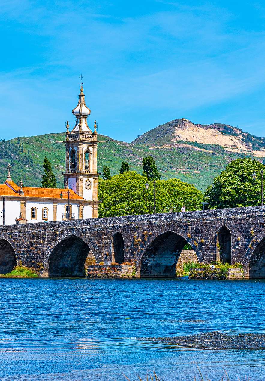 Pont à arcs dans la ville de Viana do Castelo, avec le fleuve bleu et montagnes vertes derrière la tour de l'église