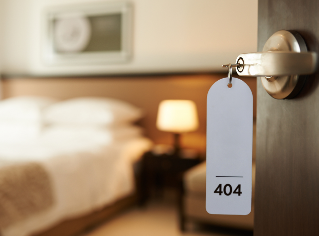 Image of an open hotel room door with a tablet displaying '404' as the room number, symbolizing a Page Not Found