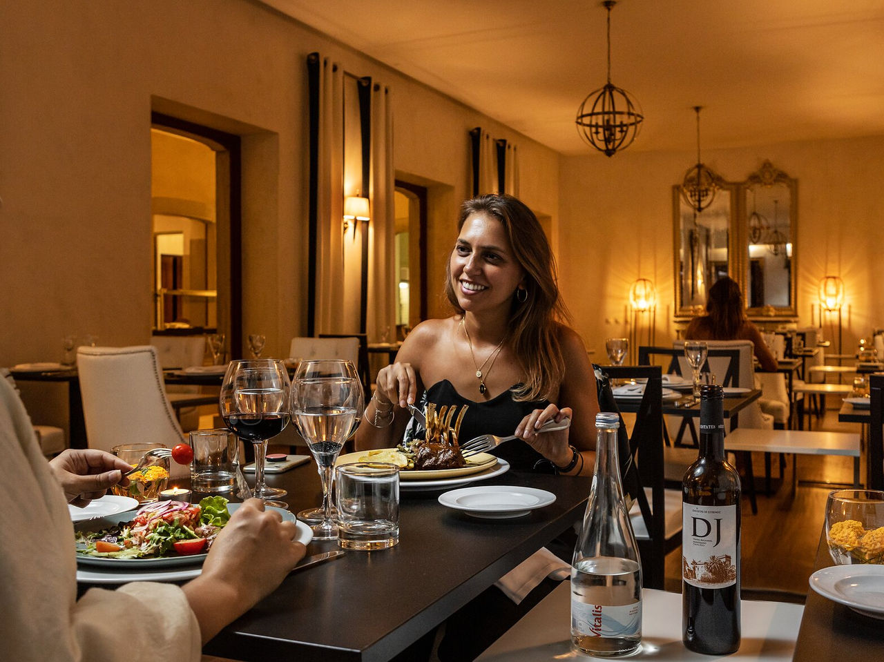 Restaurant Visconde, in het Historisch Hotel in Faro, heeft een vrouw die aan een tafel voor twee eet, met streekgerechten