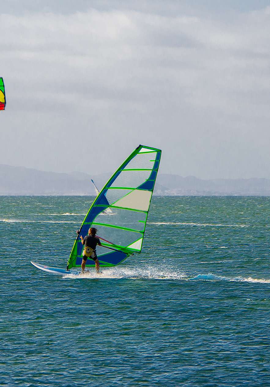 Mensen kitesurfen op het strand van Aveiro op een winderige dag met blauwe lucht