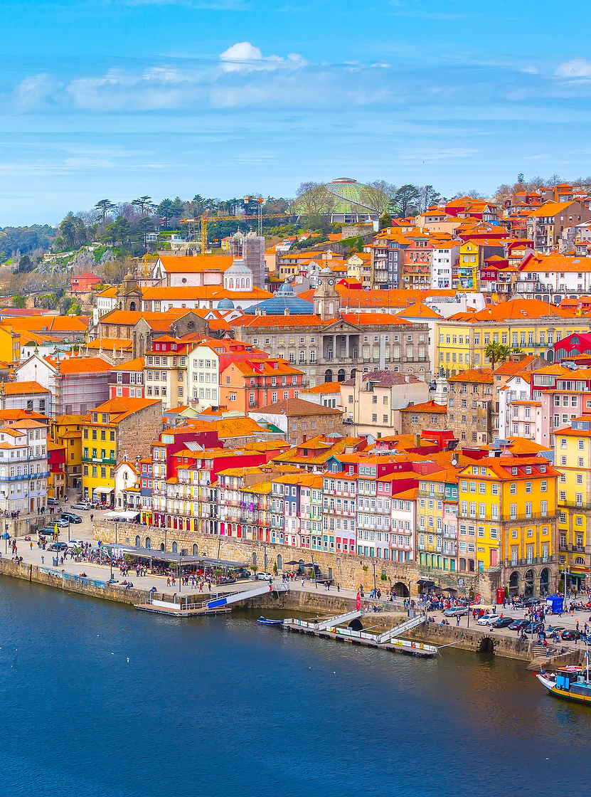 Pessoas apreciando a vista da Ribeiro do Porto, um local histórico e turístico sobre o rio Douro e a Ponte Dom Luís I