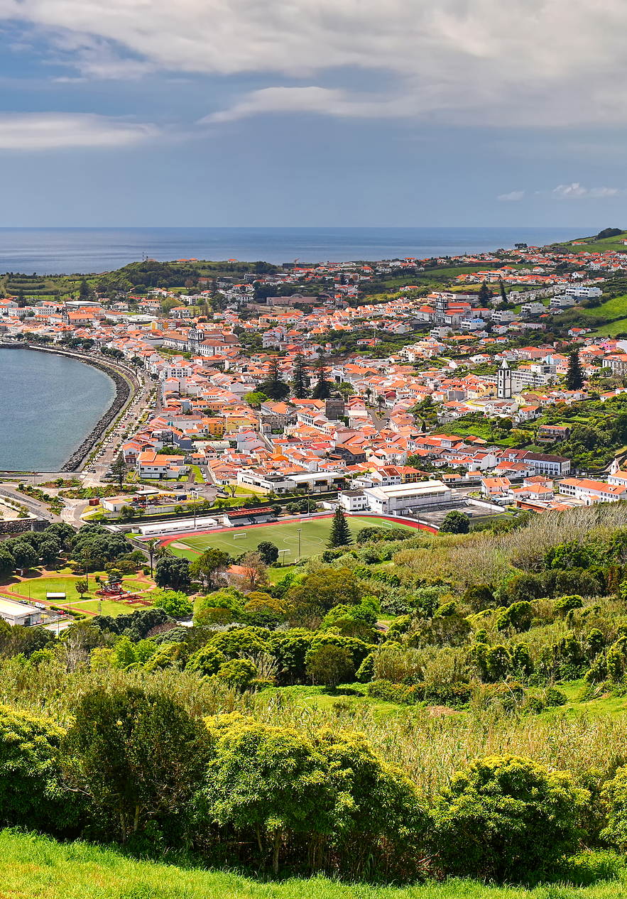 Vista da cidade da Horta, na ilha do Faial, nos Açores, com o porto repleto de barcos, casas coloridas e montanhas verdes