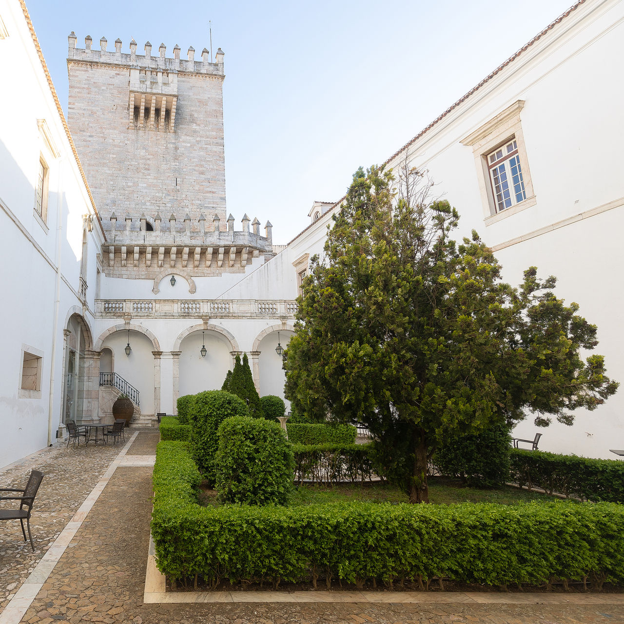 Vista do pátio interior do hotel Histórico em Estremoz no Alentejo, com um jardim, uma esplanada e uma torre ao fundo