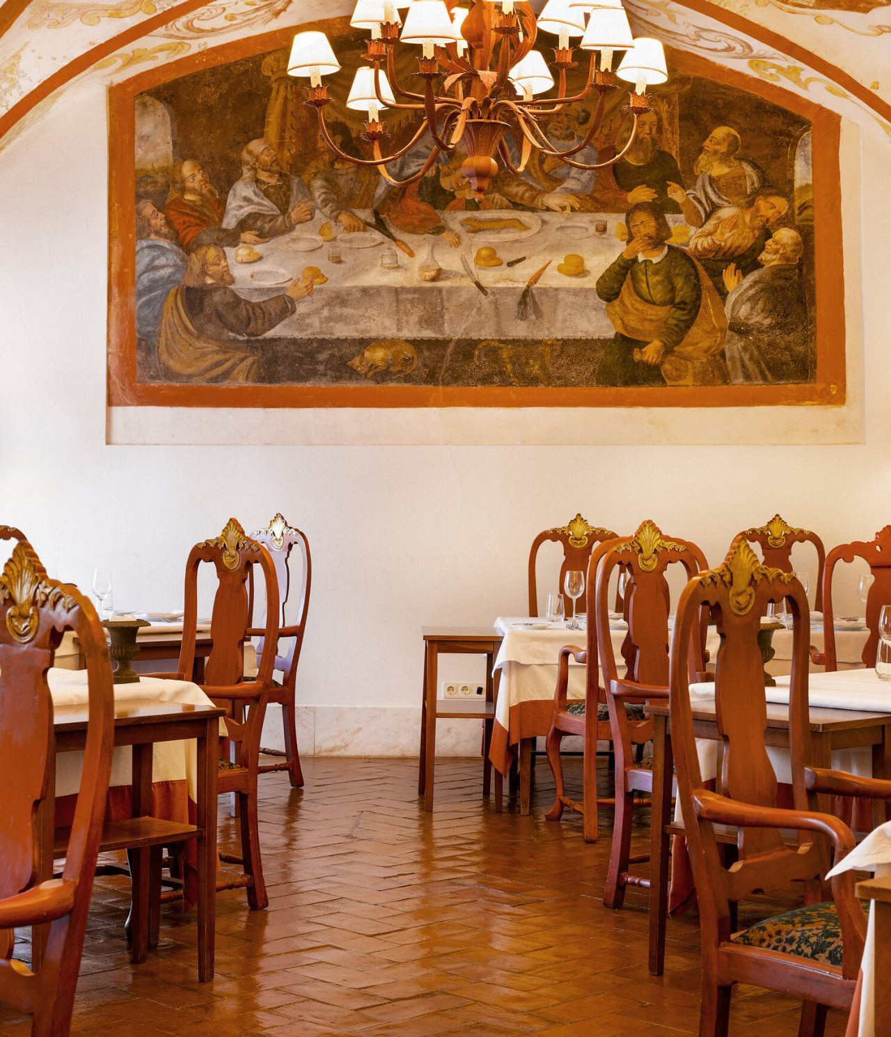 O restaurante Antigo Refeitório, do Hotel Histórico em Vila Viçosa, tem uma sala com várias mesas e cadeiras em madeira