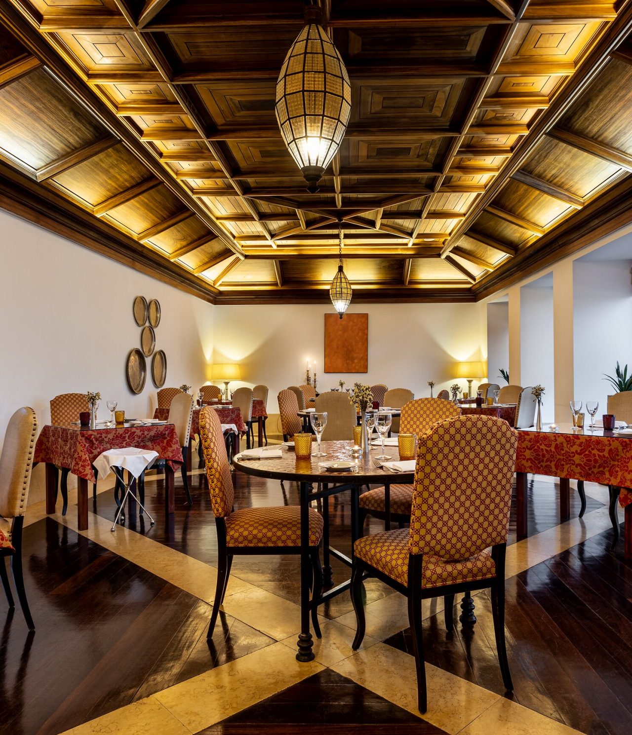 O restaurante Mouraria, do Hotel no Centro Histórico de Tavira, tem várias mesas e teto trabalhado em madeira