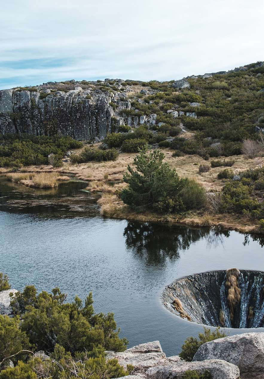 Covão dos Conchos, uma lagoa na Serra da Estrela, com vegetação rasteira em redor, e um misterioso buraco no meio da lagoa