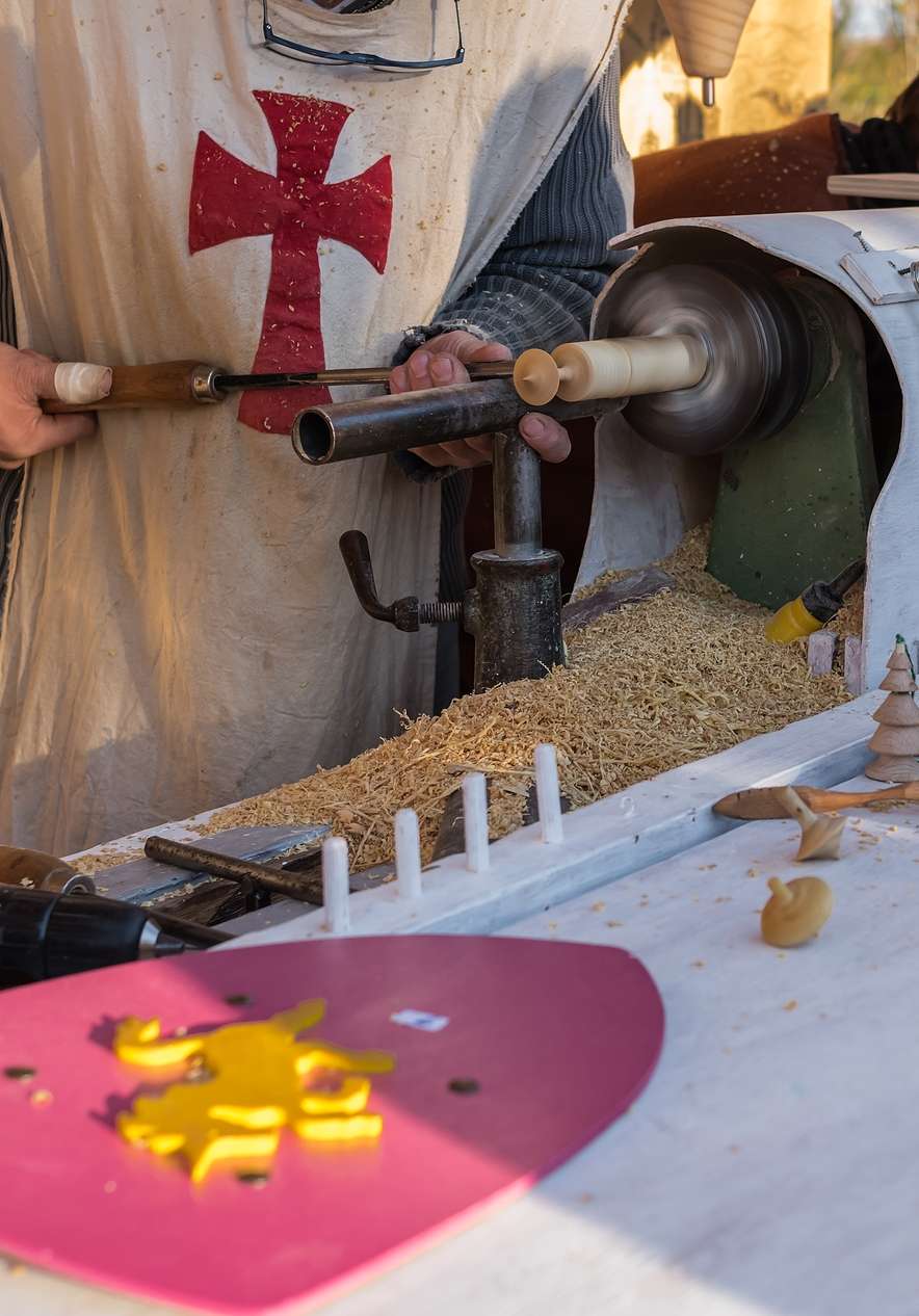 Homem na Feira Medieval de Óbidos, com traje de cavaleiro, a trabalhar em artesanato