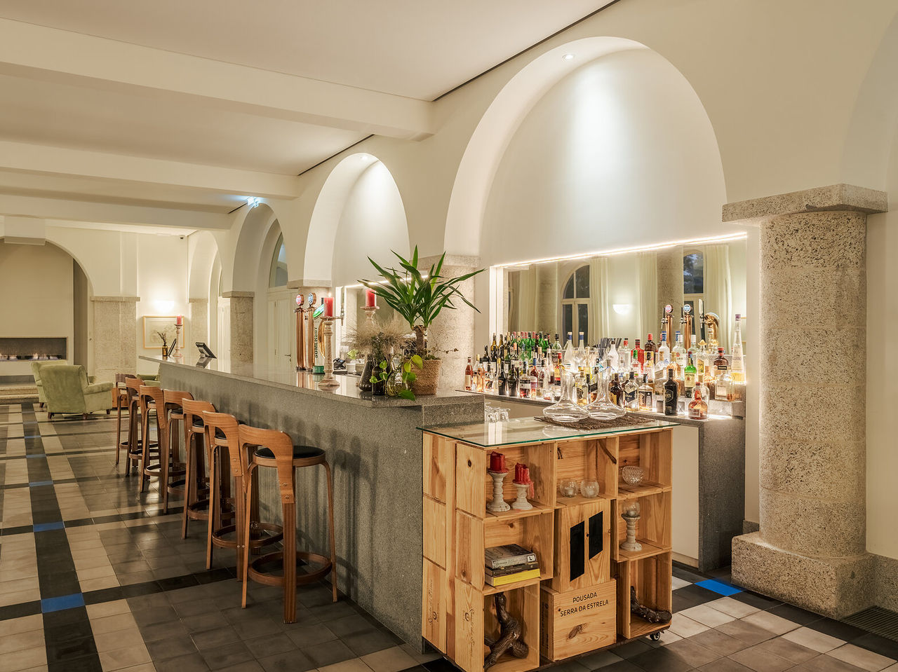Bar da Pousada Serra da Estrela, balcão de pedra com garrafas e bancos altos em ambiente iluminado