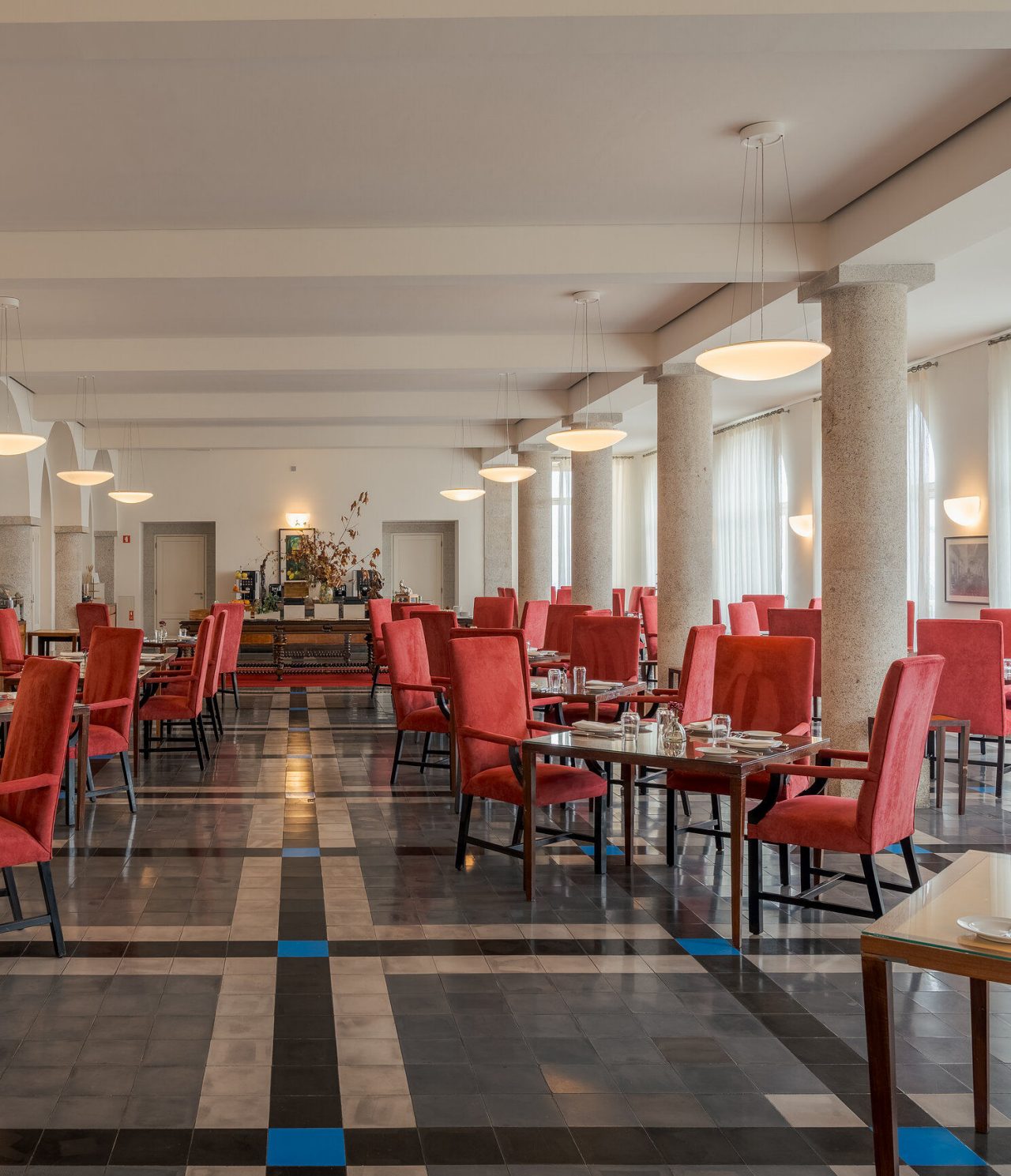 Restaurante da Pousada Serra da Estrela, sala ampla com cadeiras vermelhas e colunas de pedra