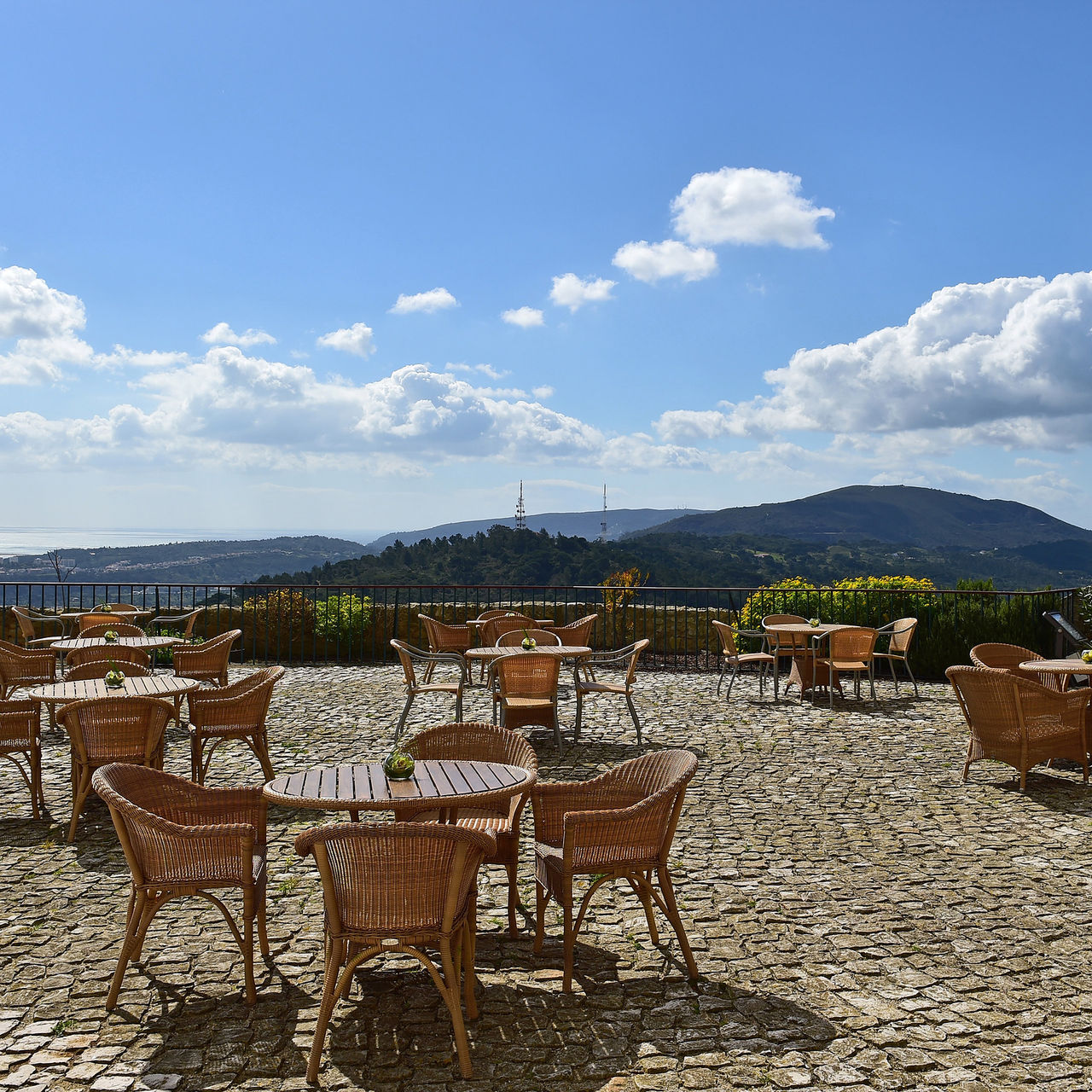 Terraço da Pousada Castelo Palmela, Hotel com Vista para a Serra da Arrábida, com cadeiras e mesas sobre piso de pedra