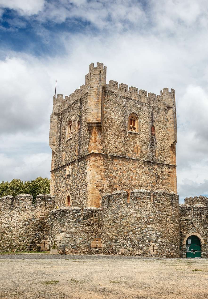 Torre medieval do Castelo de Bragança, uma construção de pedra, cercada por uma muralha circular de pedras rústicas