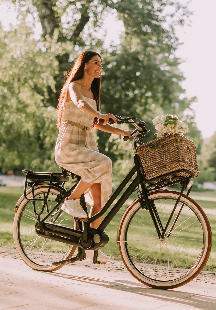 Senhora com vestido aos quadrados a andar de bicicleta num jardim junto à Pousada Mosteiro Guimarães