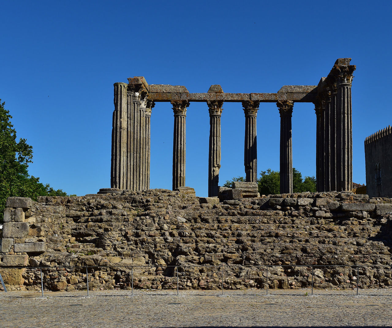 Hotel Alentejo apresentando ruínas de templo romano com colunas antigas sob céu azul intenso e muralhas de pedra