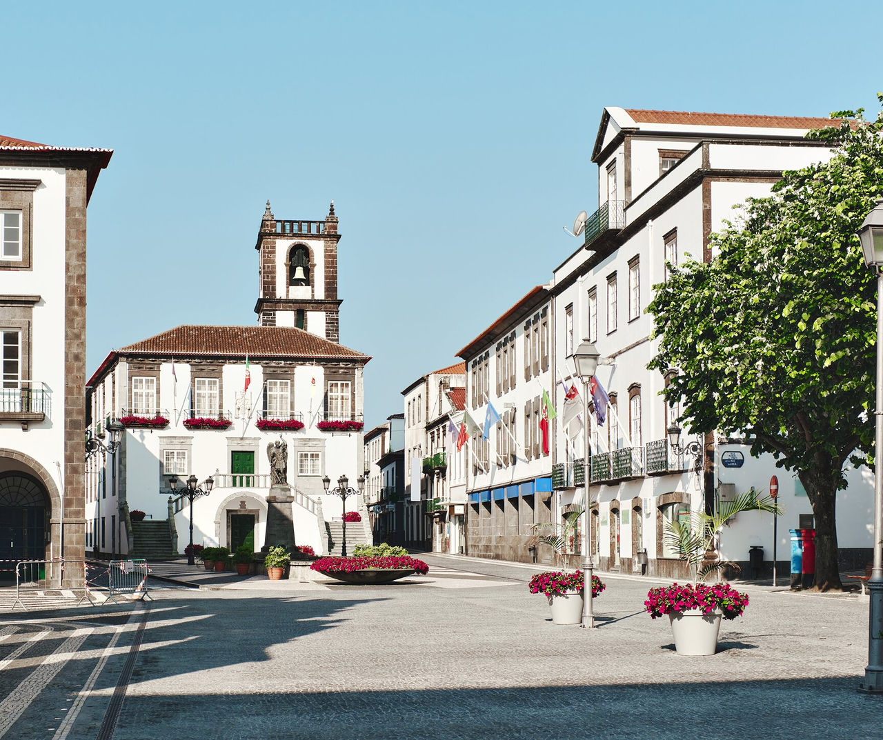 Azores hotel com vista para praça histórica com edifícios brancos, flores vermelhas e torre sineira ao fundo