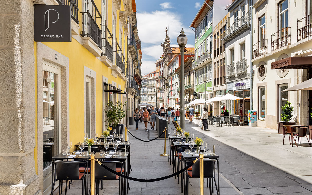 Explore Pousadas de Portugal com vista para uma rua pedonal com esplanadas e fachadas coloridas ao sol
