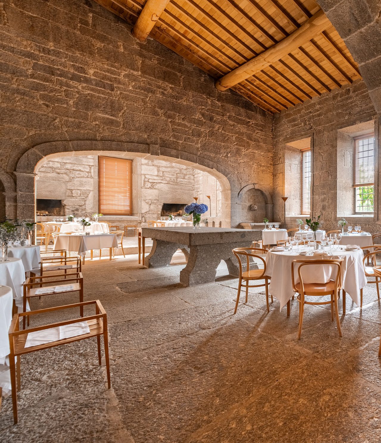 Descubra Pousadas de Portugal apresentando salão de restaurante em pedra com mesas elegantes e luz natural
