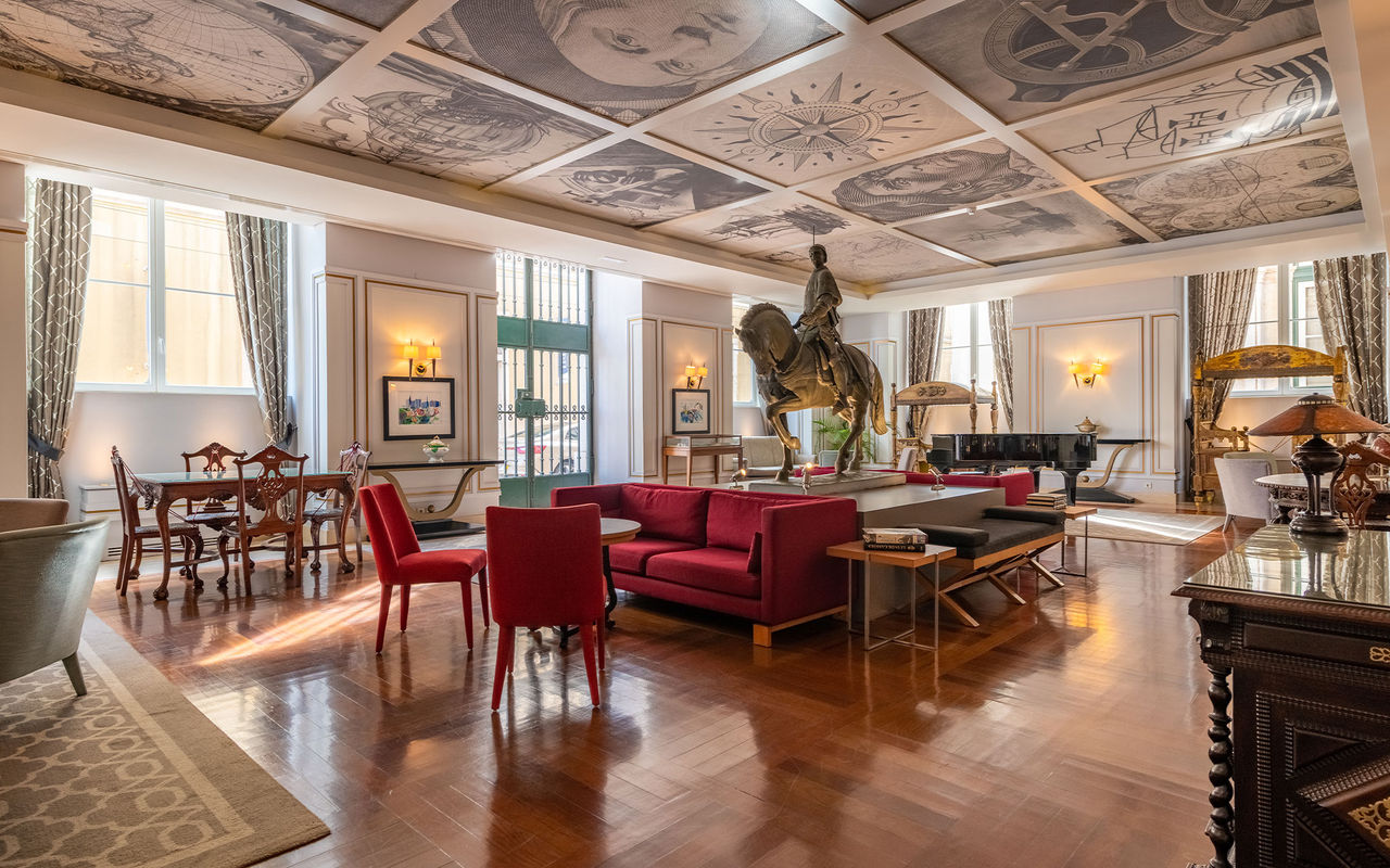 Sala elegante com sofás vermelhos, estátua equestre central e teto decorado com desenhos históricos