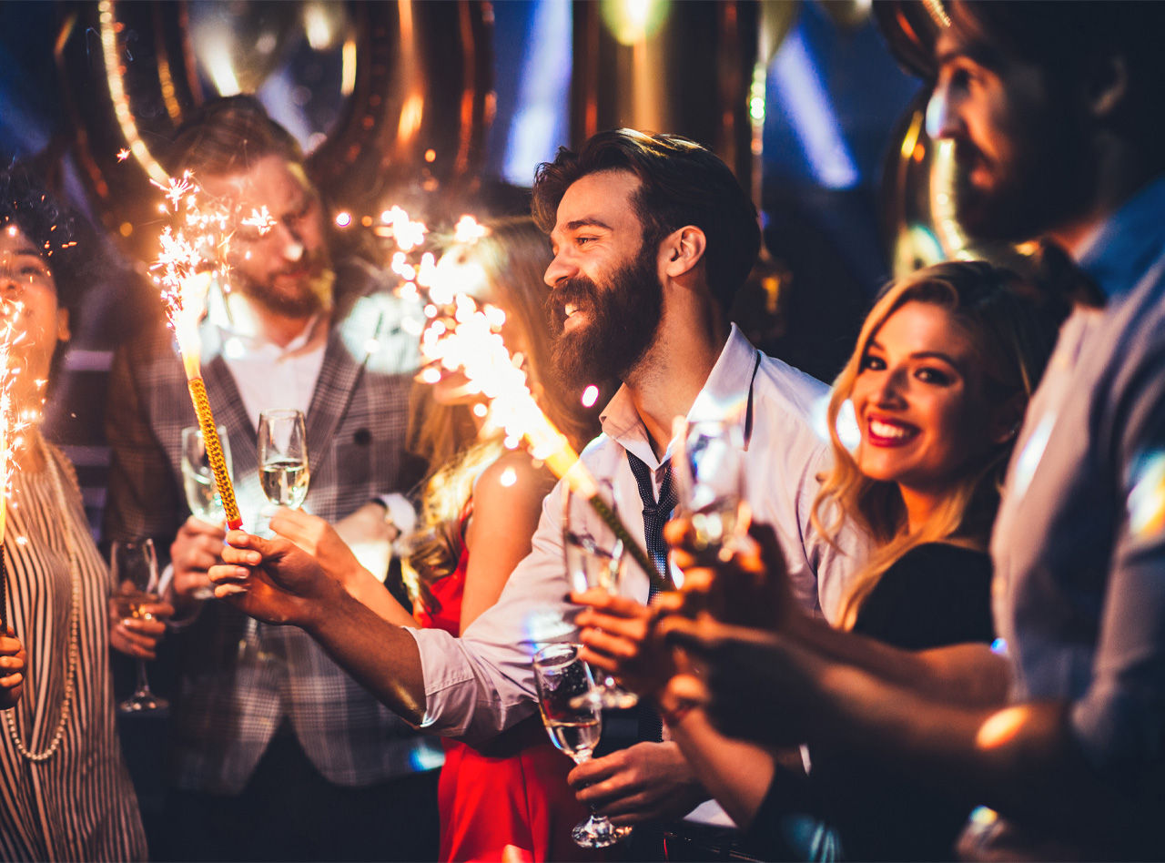 Grupo de amigos celebra a Passagem de Ano no Pestana Hotel Group, com copos de champanhe na mão e foguetes na outra mão
