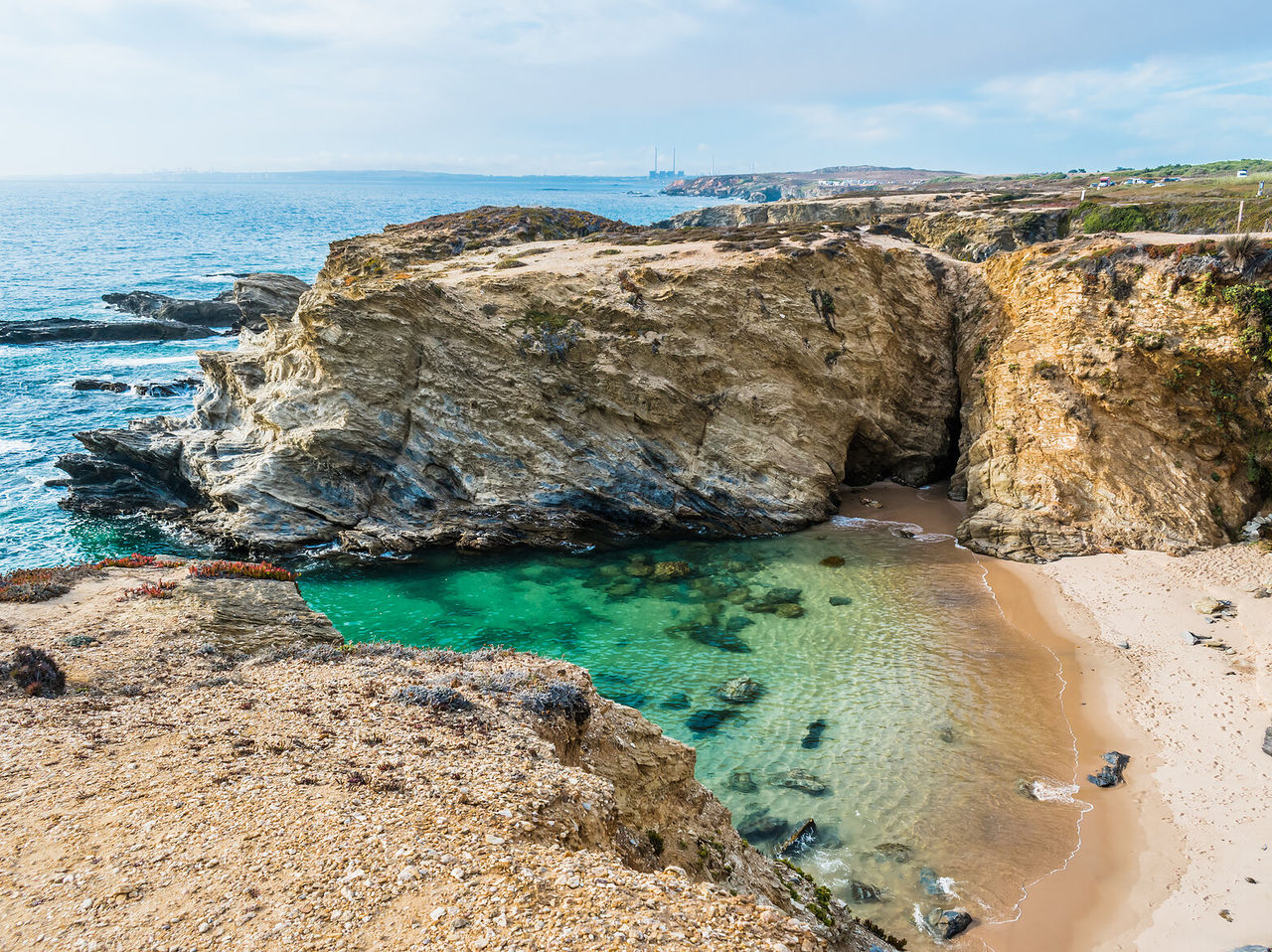 Explore Hotels in Alentejo featuring rocky coastal cliffs above a clear turquoise cove and sandy beach