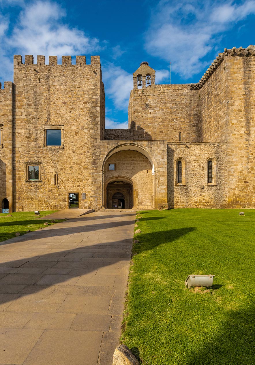 Entrada do Mosteiro de Santa Maria de Flor da Rosa perto da Pousada Mosteiro Crato, com paredes de pedra e céu azul