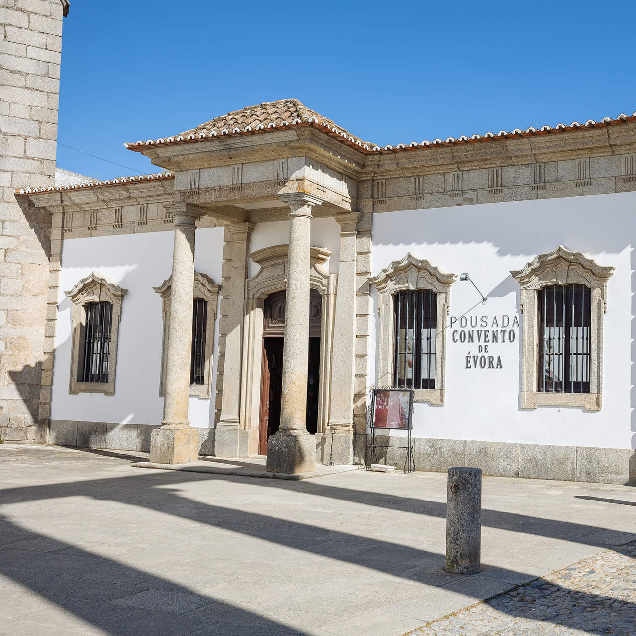 Entrance of Pousada Convento Évora, Historic Hotel in Évora, with white facade, columns and stone details