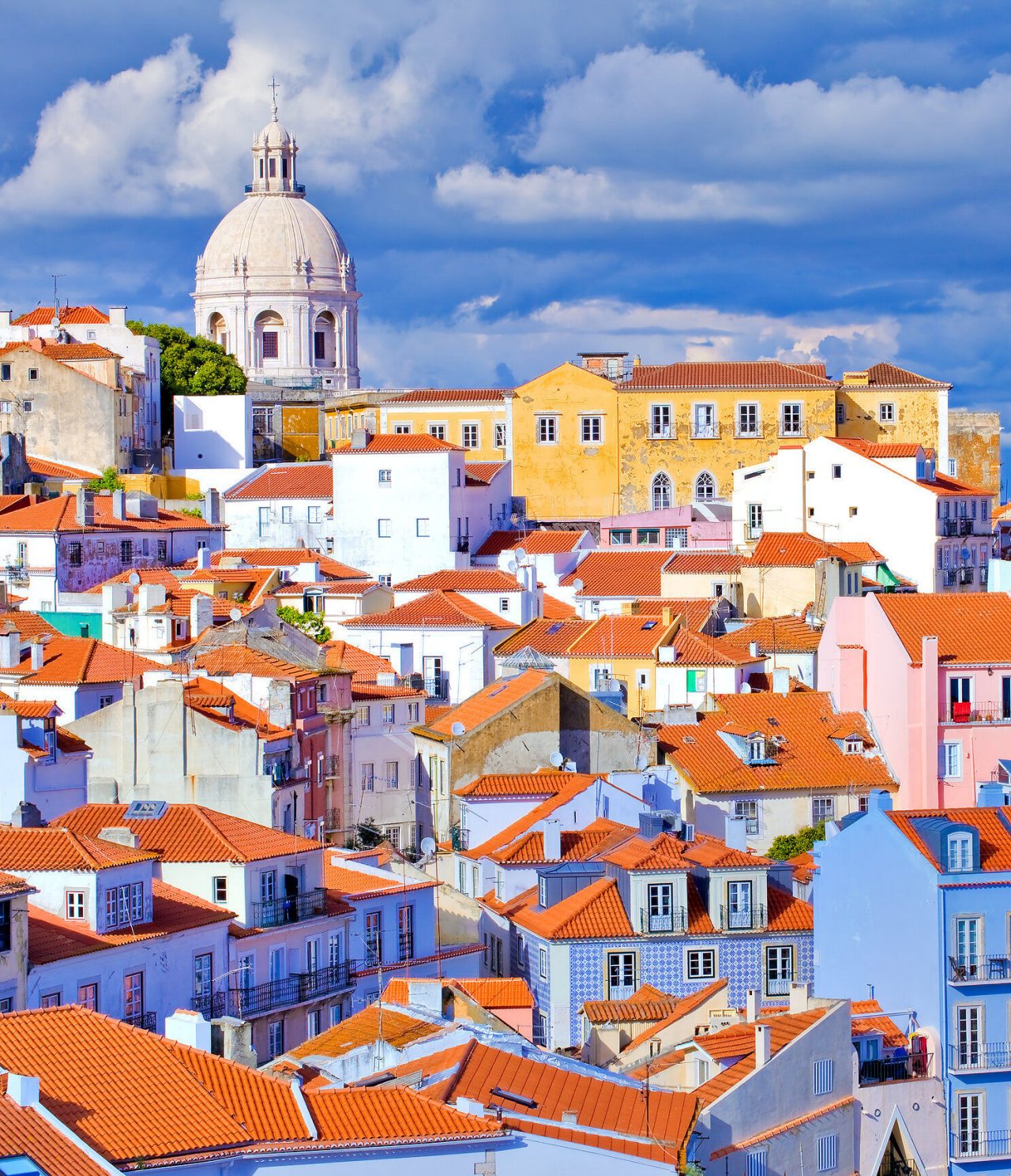 Historic center of Lisbon, with typical buildings, brick roofs, and a basilica in the background