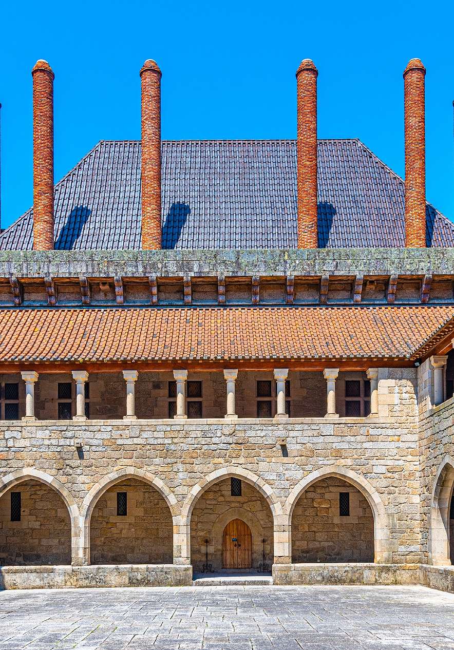 View of the inner courtyard of the Palace of the Dukes of Bragança with stone walls arcades and several chimneys